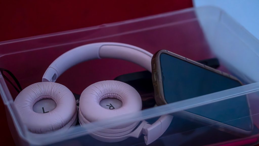 Phones and headphones in a plastic bin